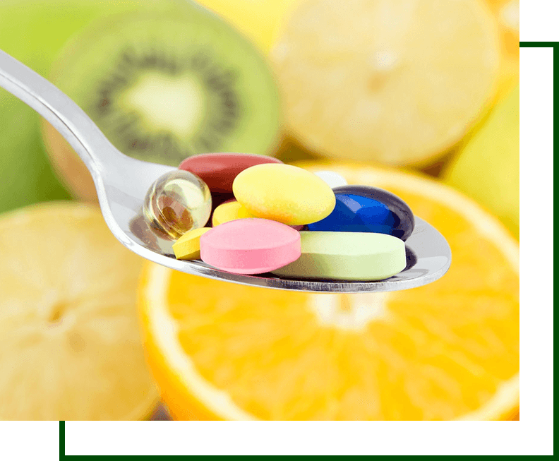 A spoon with pills on it in front of sliced fruit.