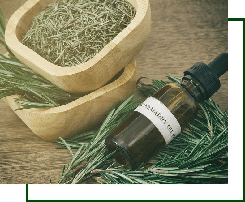 A bottle of rosemary oil next to two wooden bowls.