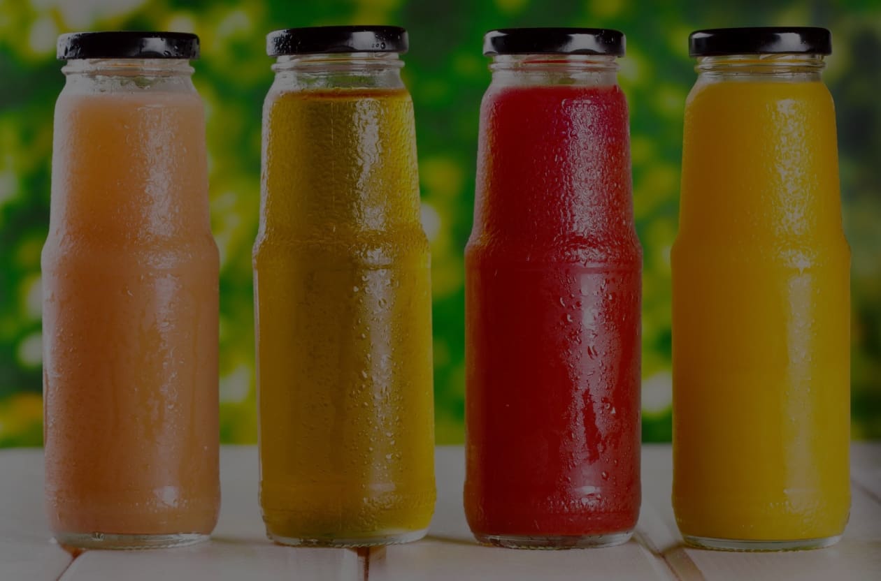 A row of juice bottles sitting on top of a table.