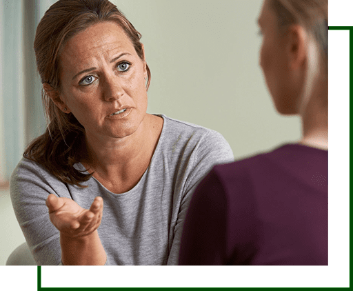 A woman is talking to another person in front of a mirror.