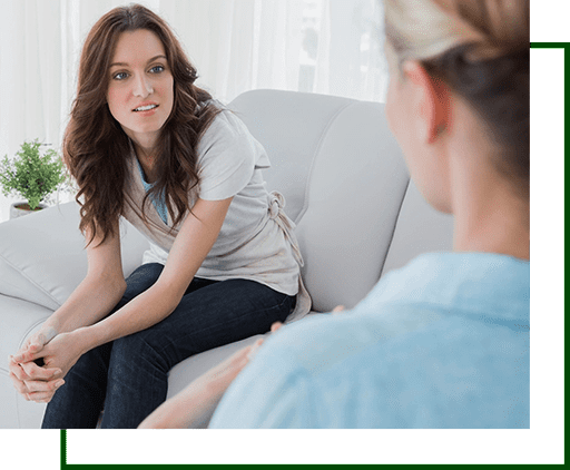 A woman sitting on the couch talking to another person.