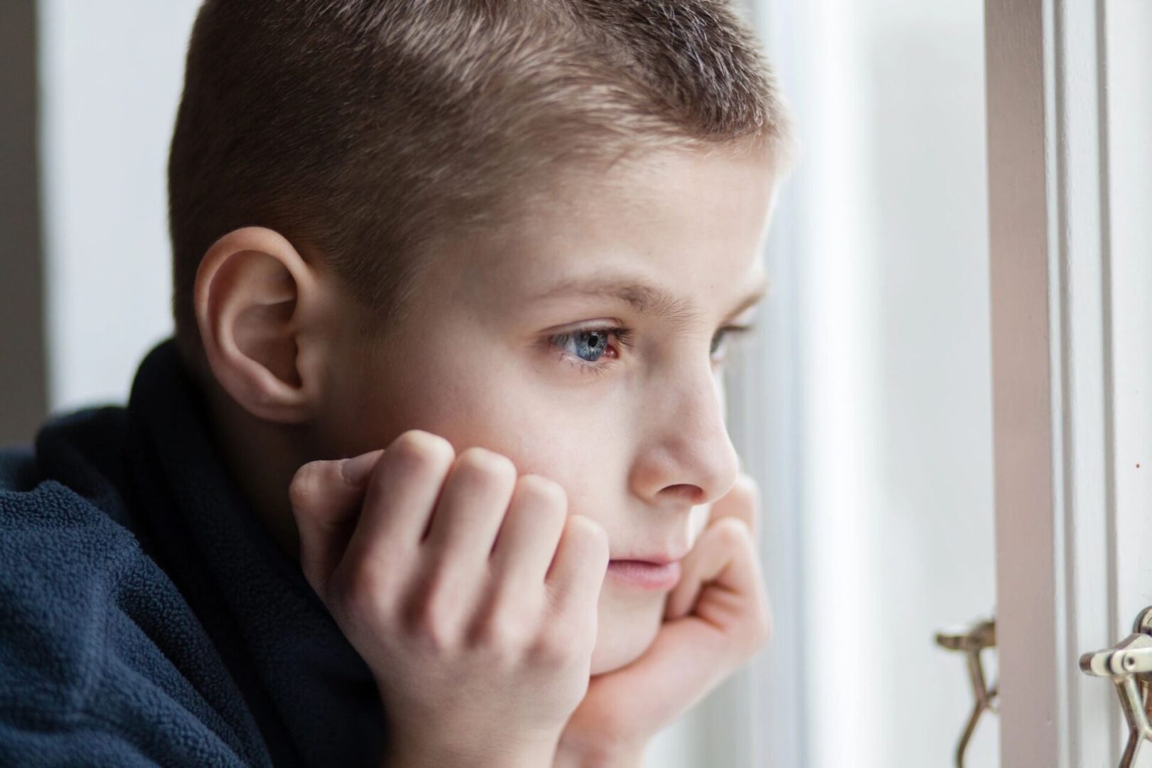 A young boy is looking out the window.